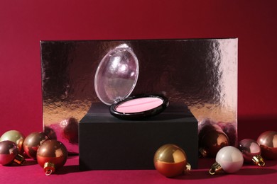 Photo of Christmas gift. Luxury cosmetic product and festive balls on dark pink background