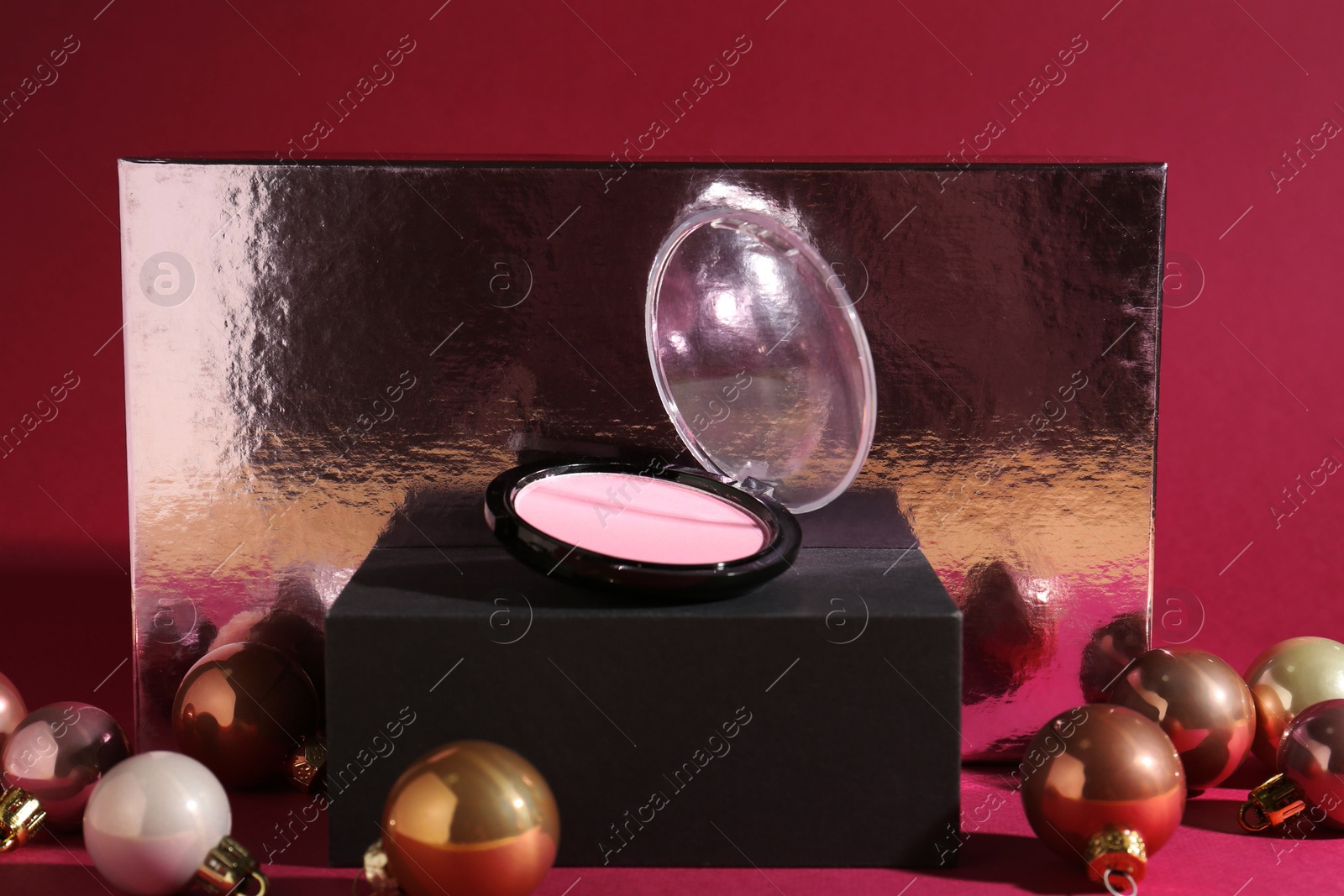 Photo of Christmas gift. Luxury cosmetic product and festive balls on dark pink background