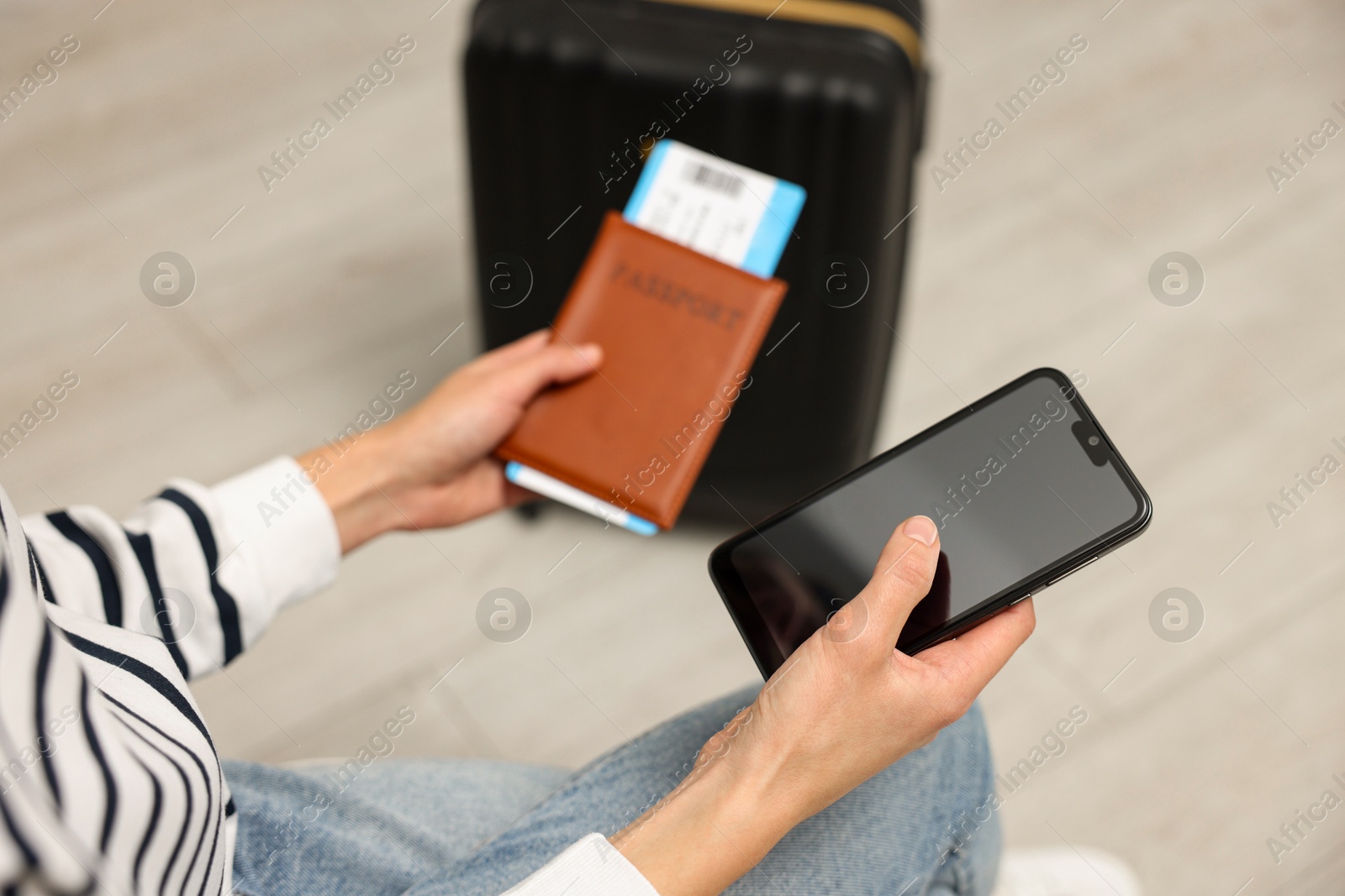 Photo of Traveller with passport, flight ticket and smartphone indoors, closeup