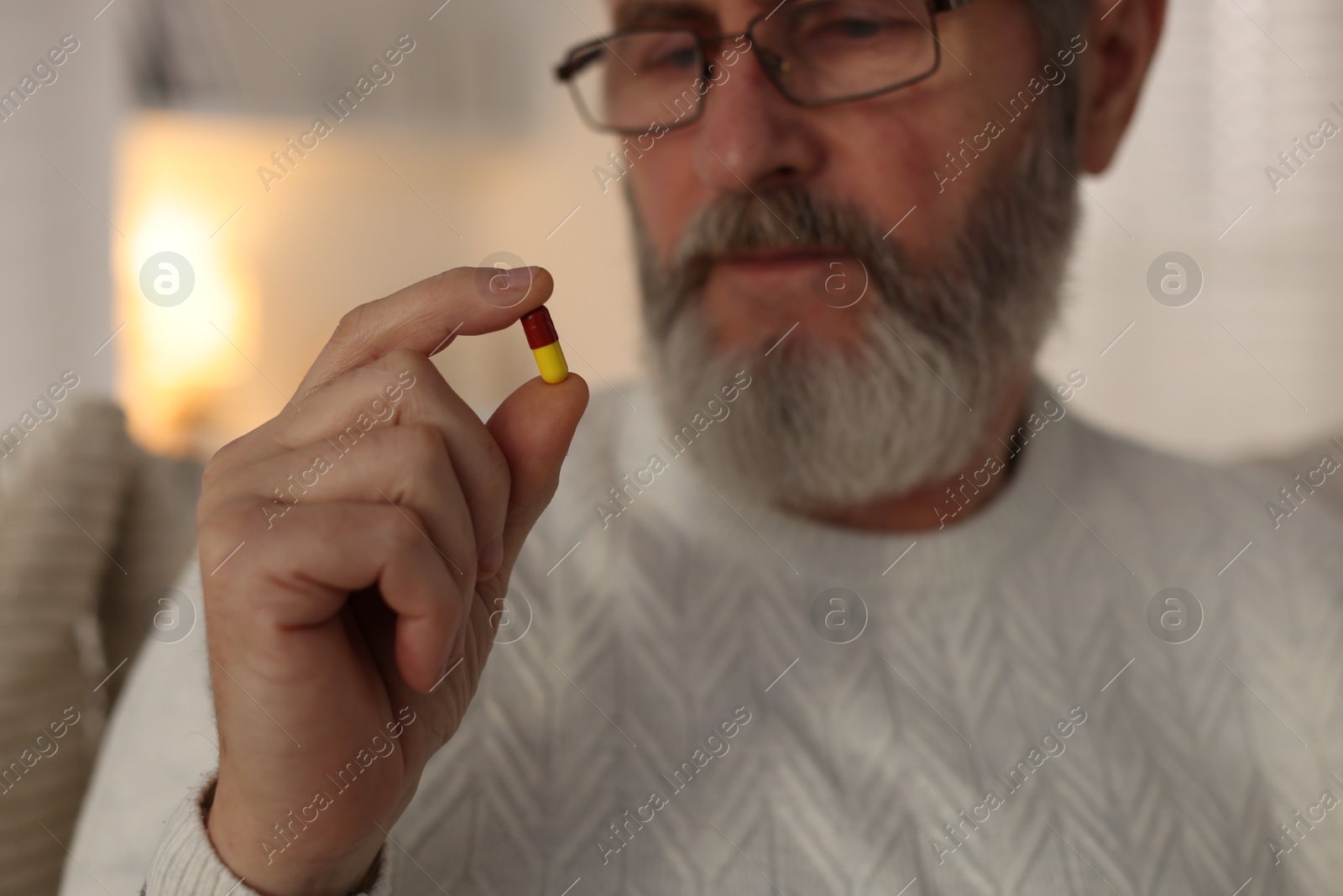 Photo of Senior man with pill at home, closeup