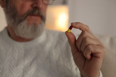 Photo of Senior man with pill at home, closeup