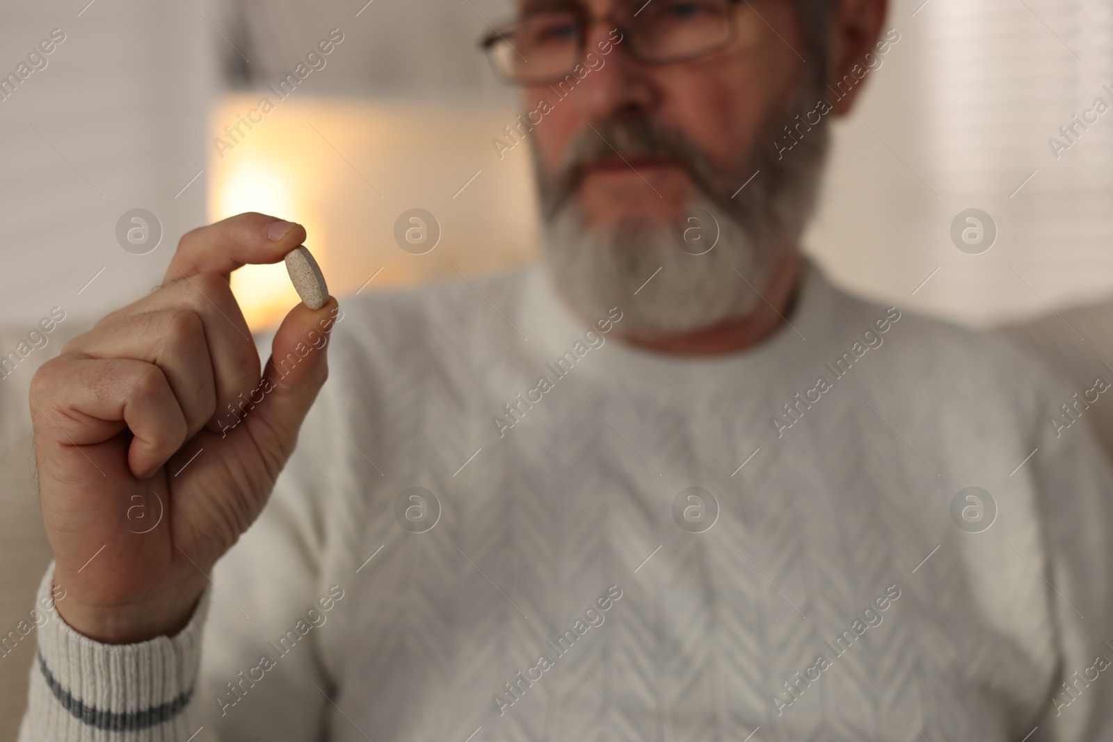 Photo of Senior man with pill at home, closeup