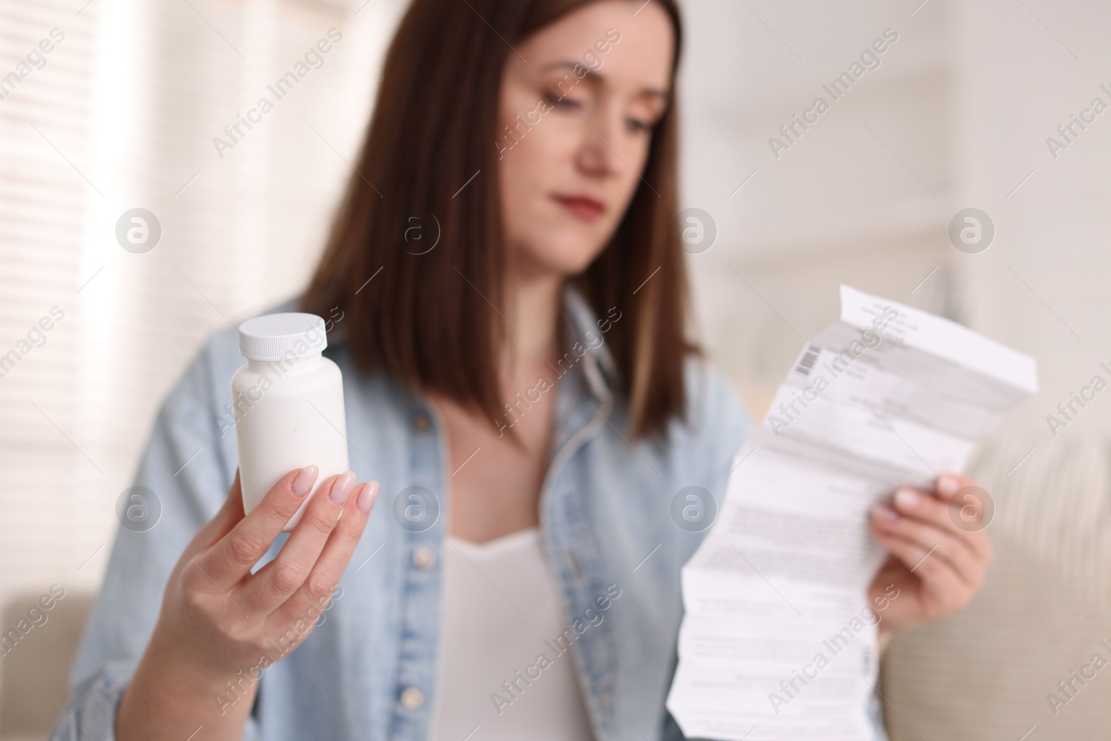 Photo of Woman with bottle of pills and instruction indoors, selective focus