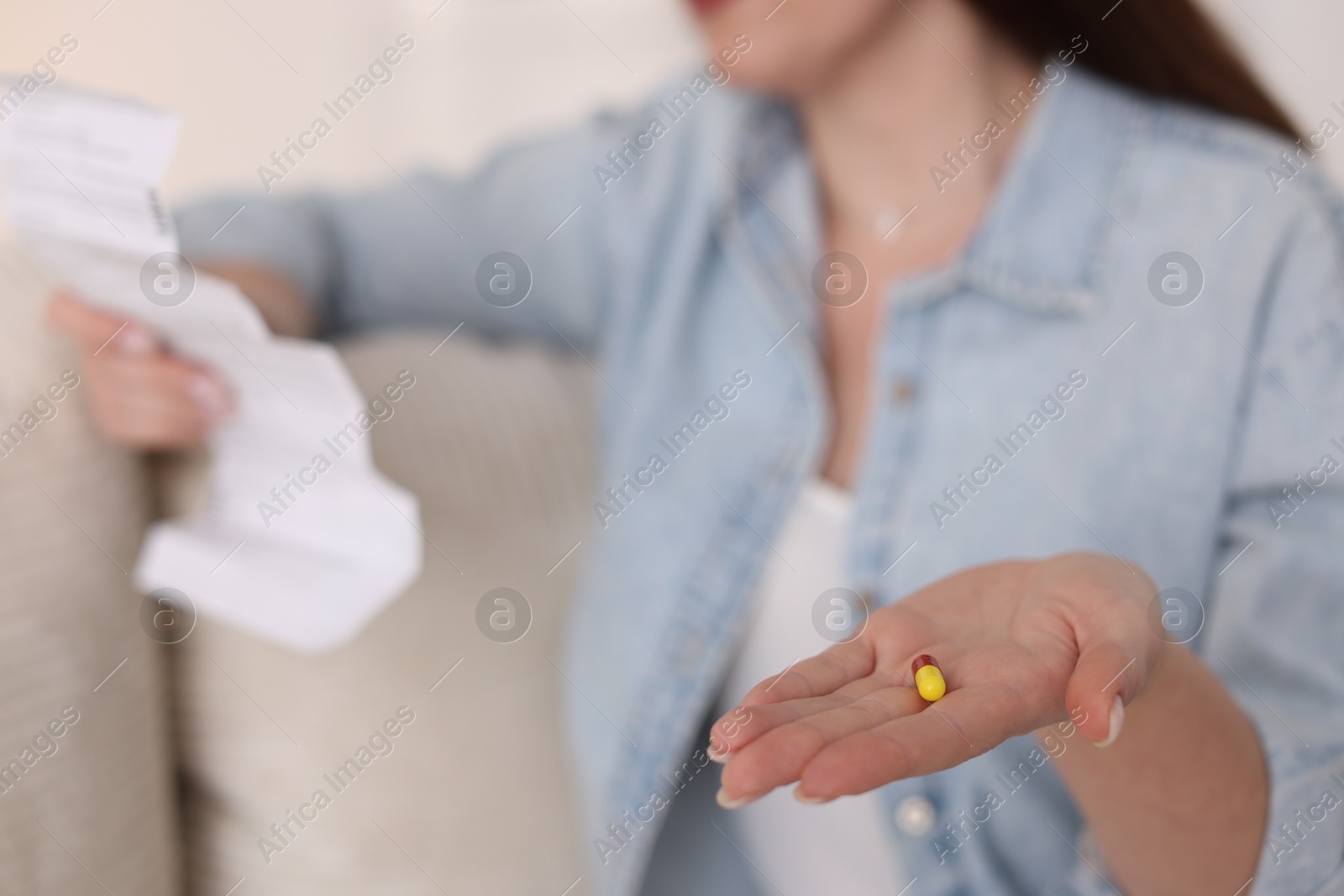 Photo of Woman with pill reading instruction indoors, selective focus