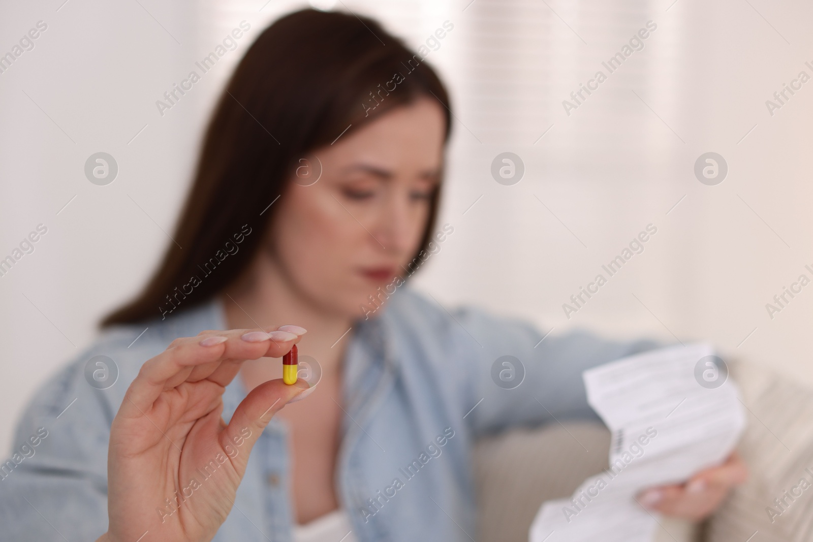 Photo of Woman with pill reading instruction indoors, selective focus