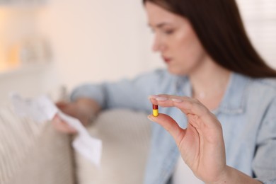 Photo of Woman with pill reading instruction indoors, selective focus