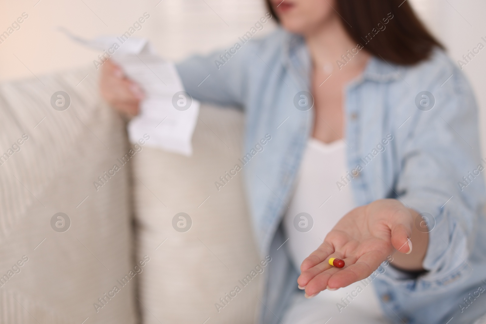 Photo of Woman with pill reading instruction indoors, selective focus