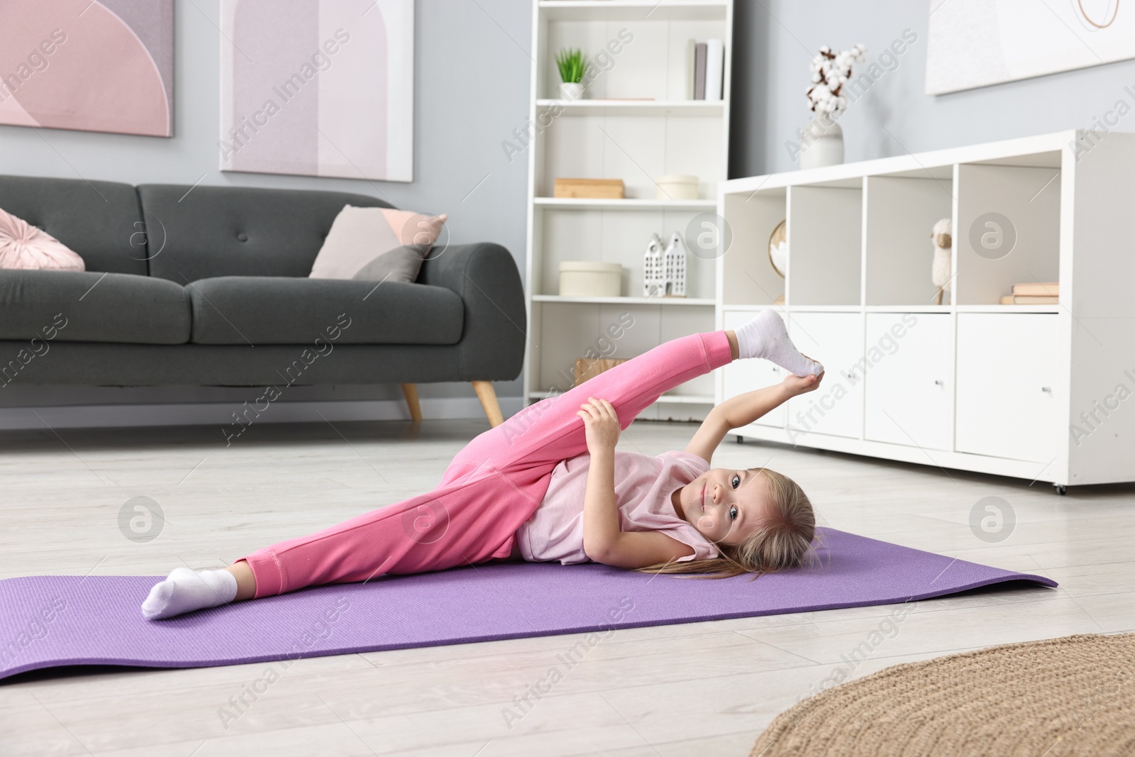 Photo of Little girl exercising on fitness mat at home. Sport activity