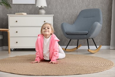 Photo of Little girl exercising on rug at home. Sport activity