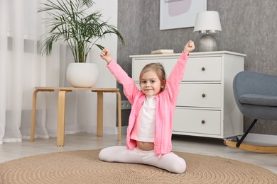 Photo of Little girl exercising on rug at home. Sport activity