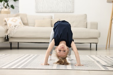 Photo of Little girl exercising on rug at home. Sport activity