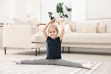 Photo of Little girl exercising on rug at home. Sport activity