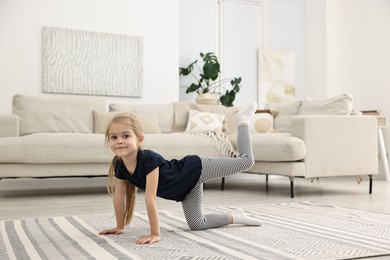 Photo of Little girl exercising on rug at home. Sport activity