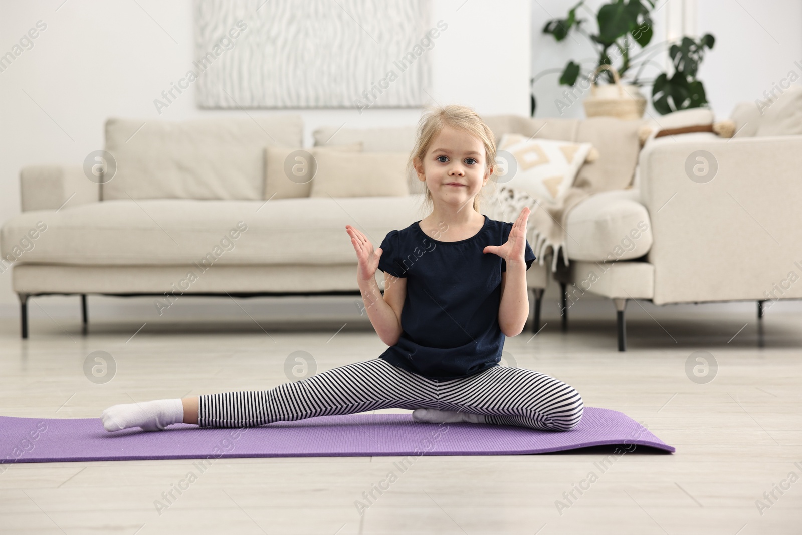 Photo of Little girl exercising on fitness mat at home. Sport activity