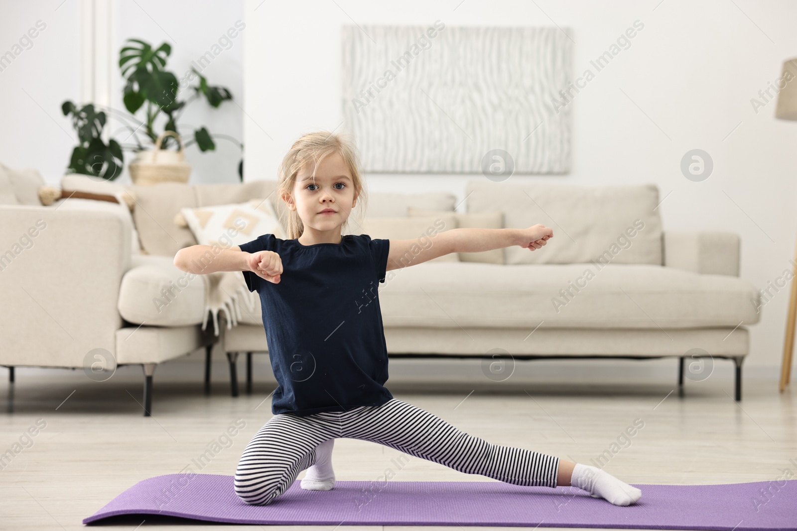 Photo of Little girl exercising on fitness mat at home. Sport activity