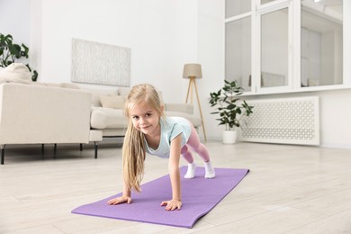 Photo of Little girl exercising on fitness mat at home. Sport activity