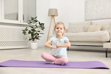 Photo of Little girl exercising on fitness mat at home. Sport activity