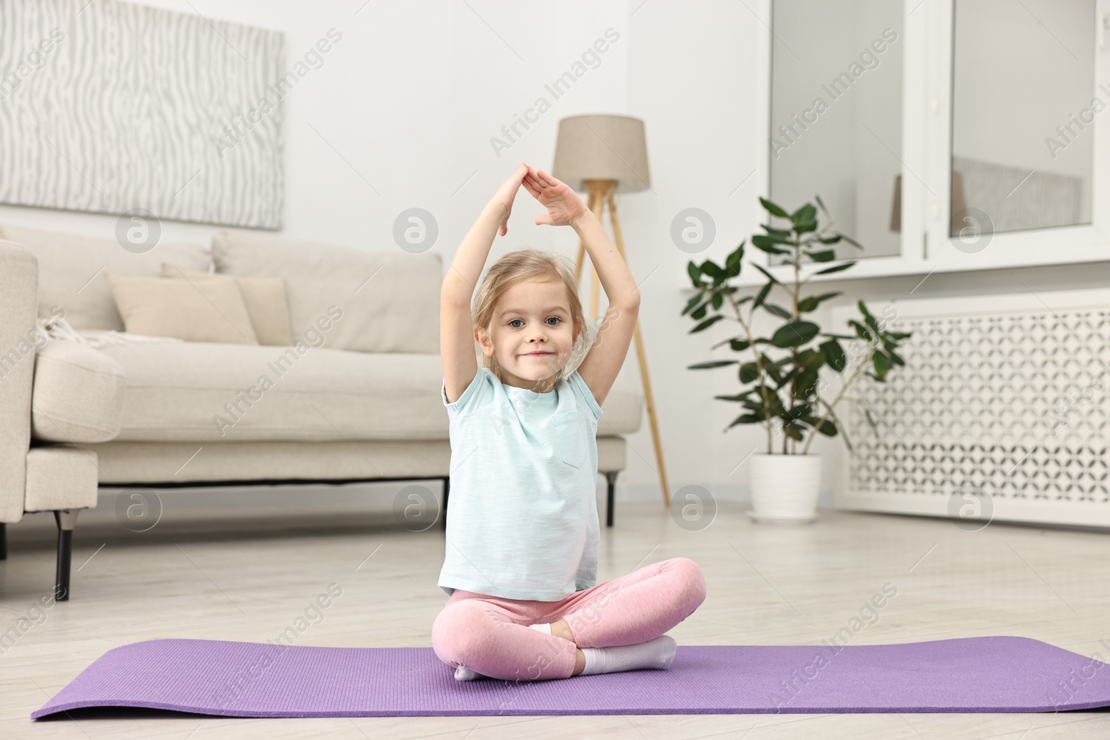 Photo of Little girl exercising on fitness mat at home. Sport activity