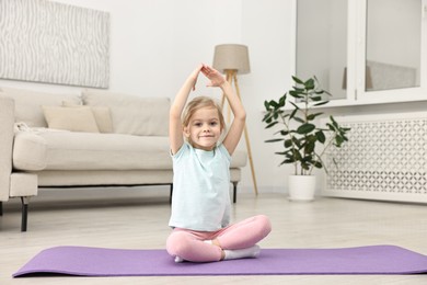 Photo of Little girl exercising on fitness mat at home. Sport activity