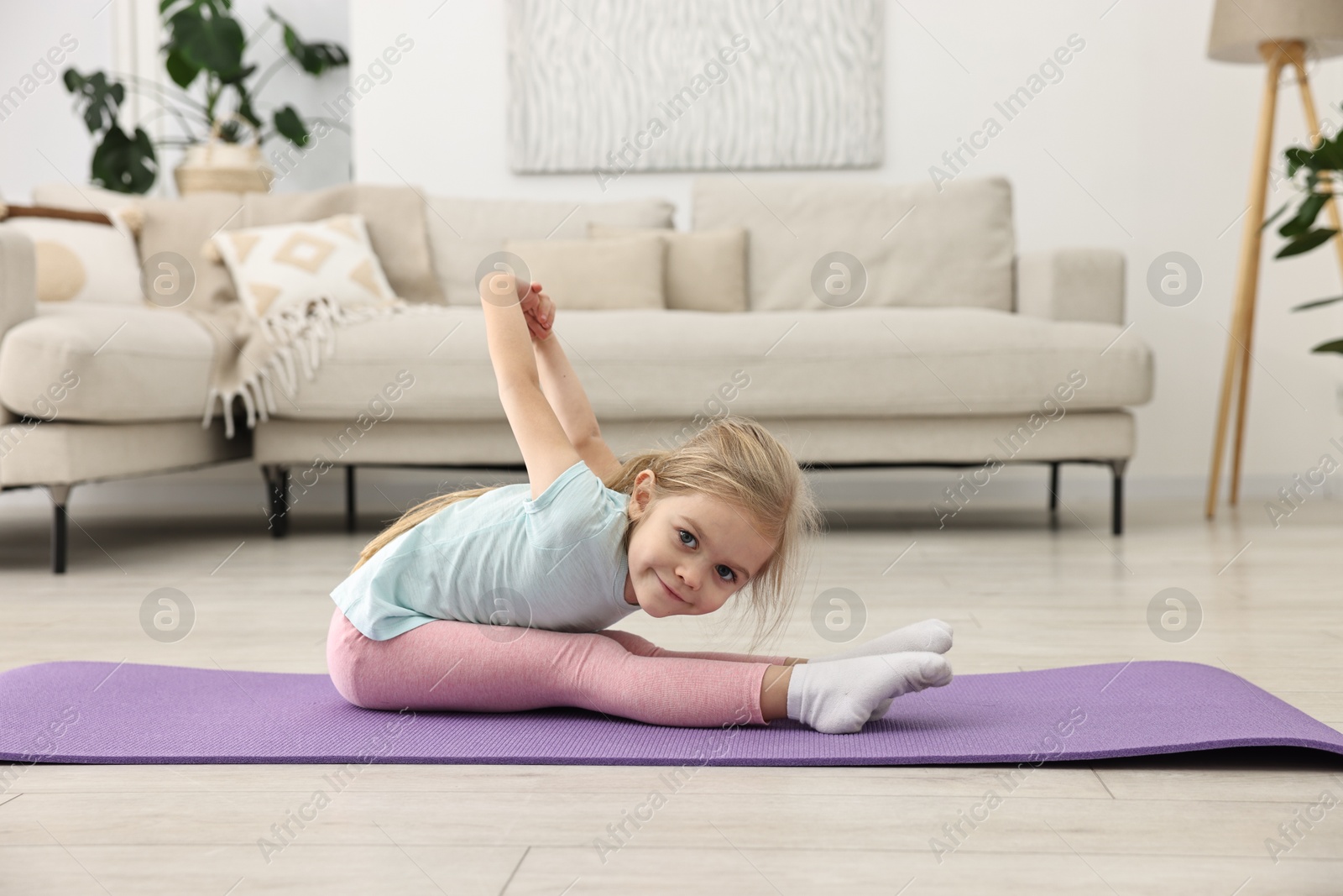 Photo of Little girl exercising on fitness mat at home. Sport activity