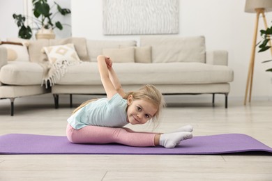 Photo of Little girl exercising on fitness mat at home. Sport activity