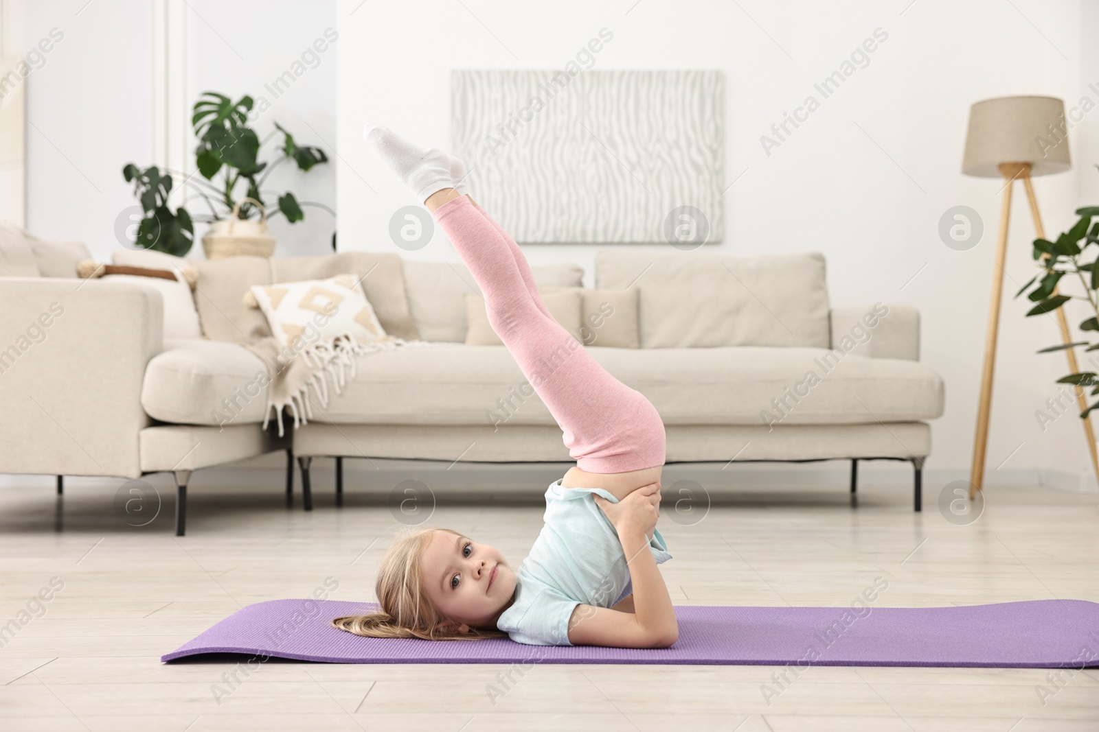 Photo of Little girl exercising on fitness mat at home. Sport activity