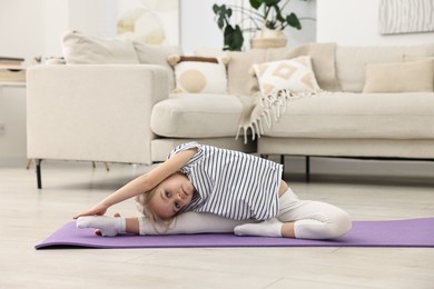 Photo of Little girl exercising on fitness mat at home. Sport activity