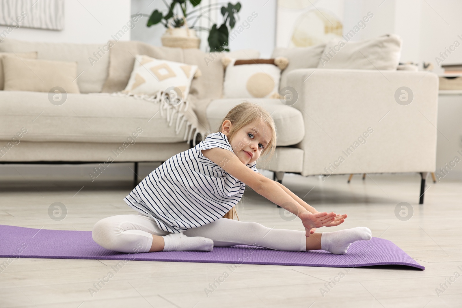 Photo of Little girl exercising on fitness mat at home. Sport activity