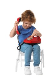 Photo of Cute little boy with telephone on step stool against white background