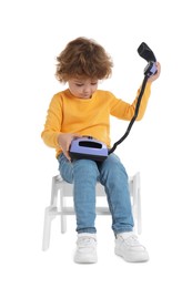 Photo of Cute little boy with telephone on step stool against white background