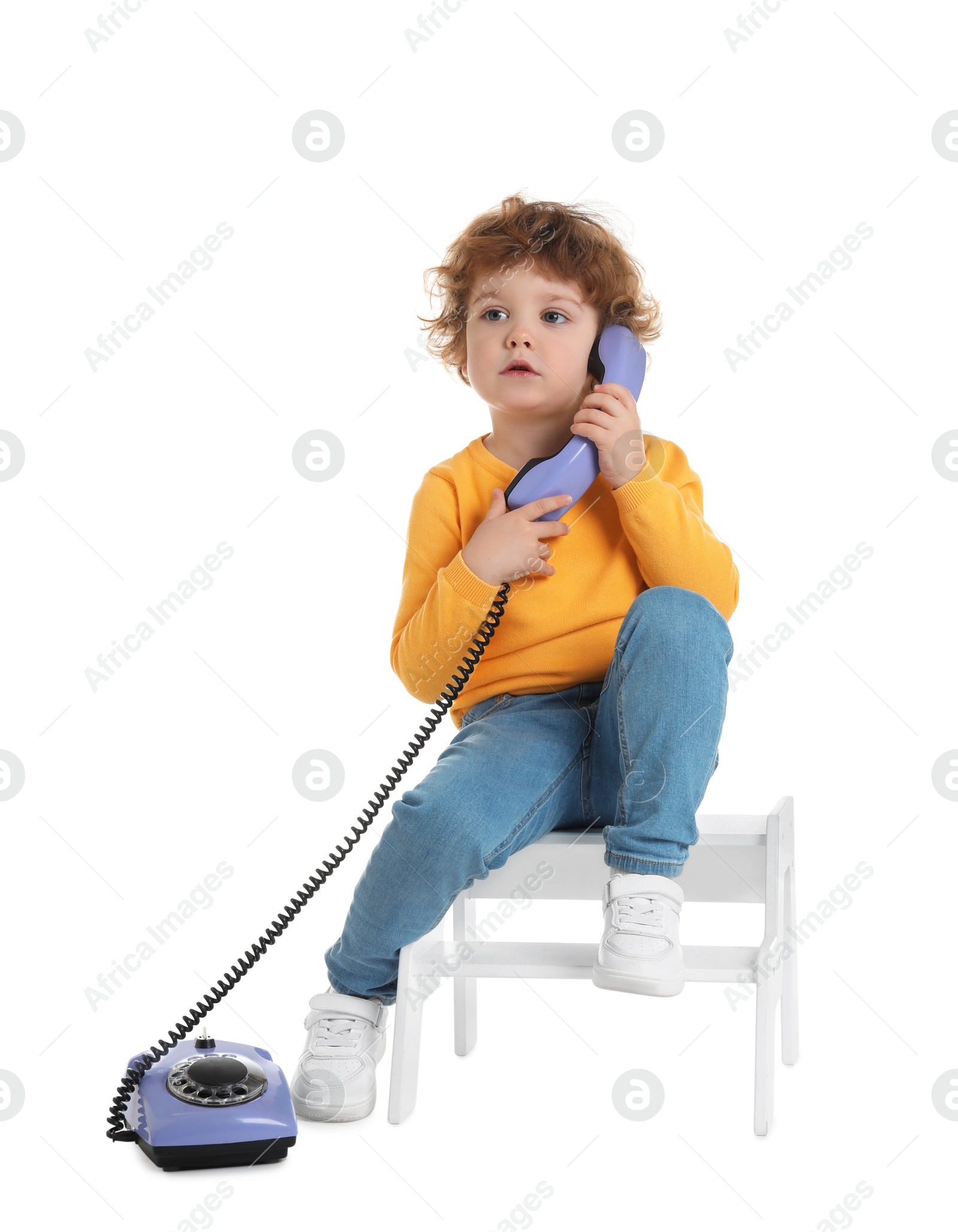 Photo of Cute little boy with telephone on step stool against white background