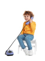 Photo of Cute little boy with telephone on step stool against white background