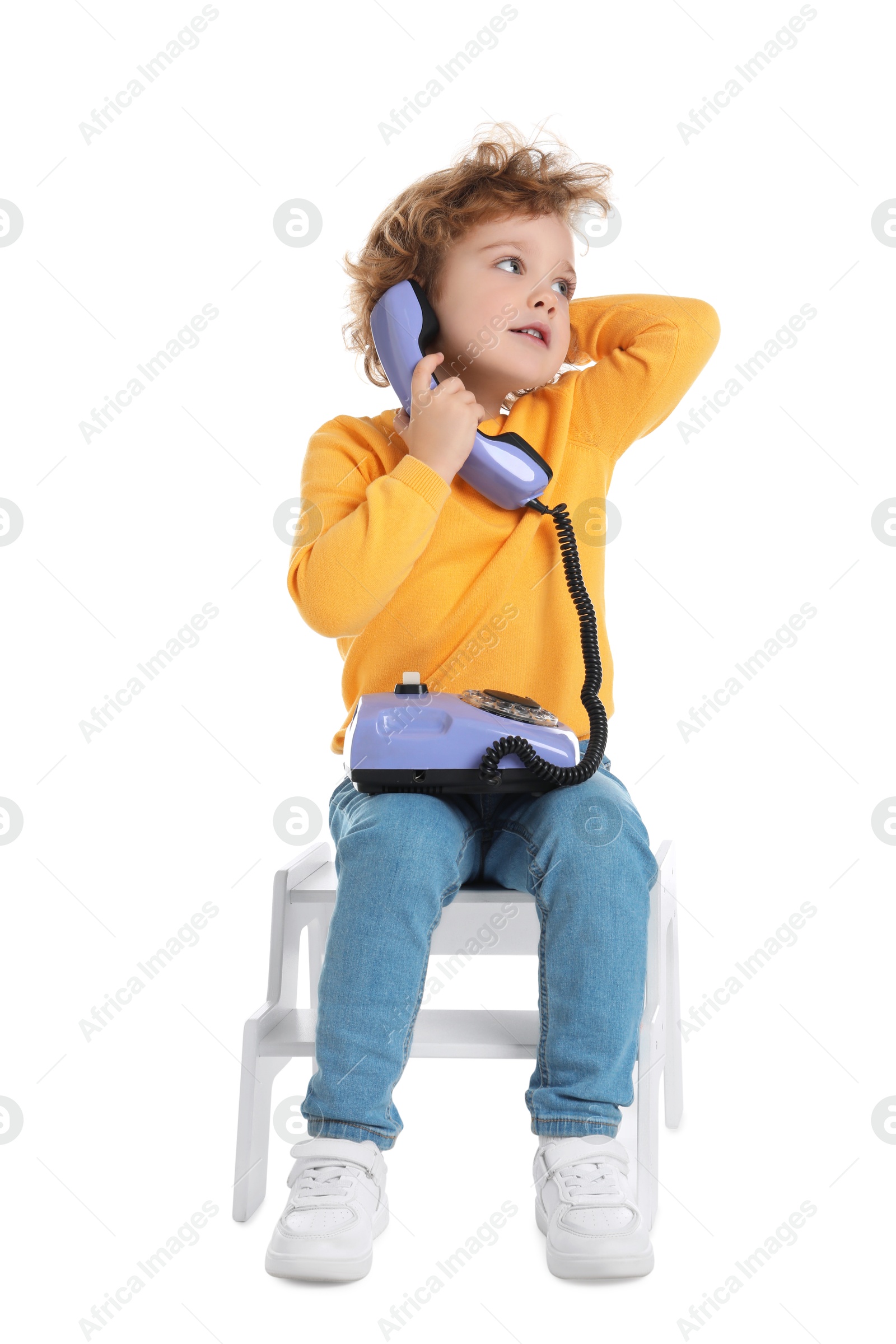 Photo of Cute little boy with telephone on step stool against white background