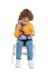 Photo of Cute little boy with telephone on step stool against white background