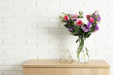 Photo of Vase with beautiful eustoma flowers on wooden chest of drawers, space for text