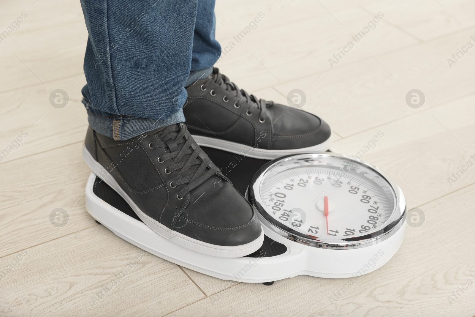 Photo of Overweight man standing on scales during consultation with nutritionist in clinic, closeup