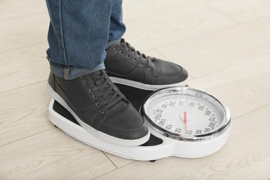 Photo of Overweight man standing on scales during consultation with nutritionist in clinic, closeup