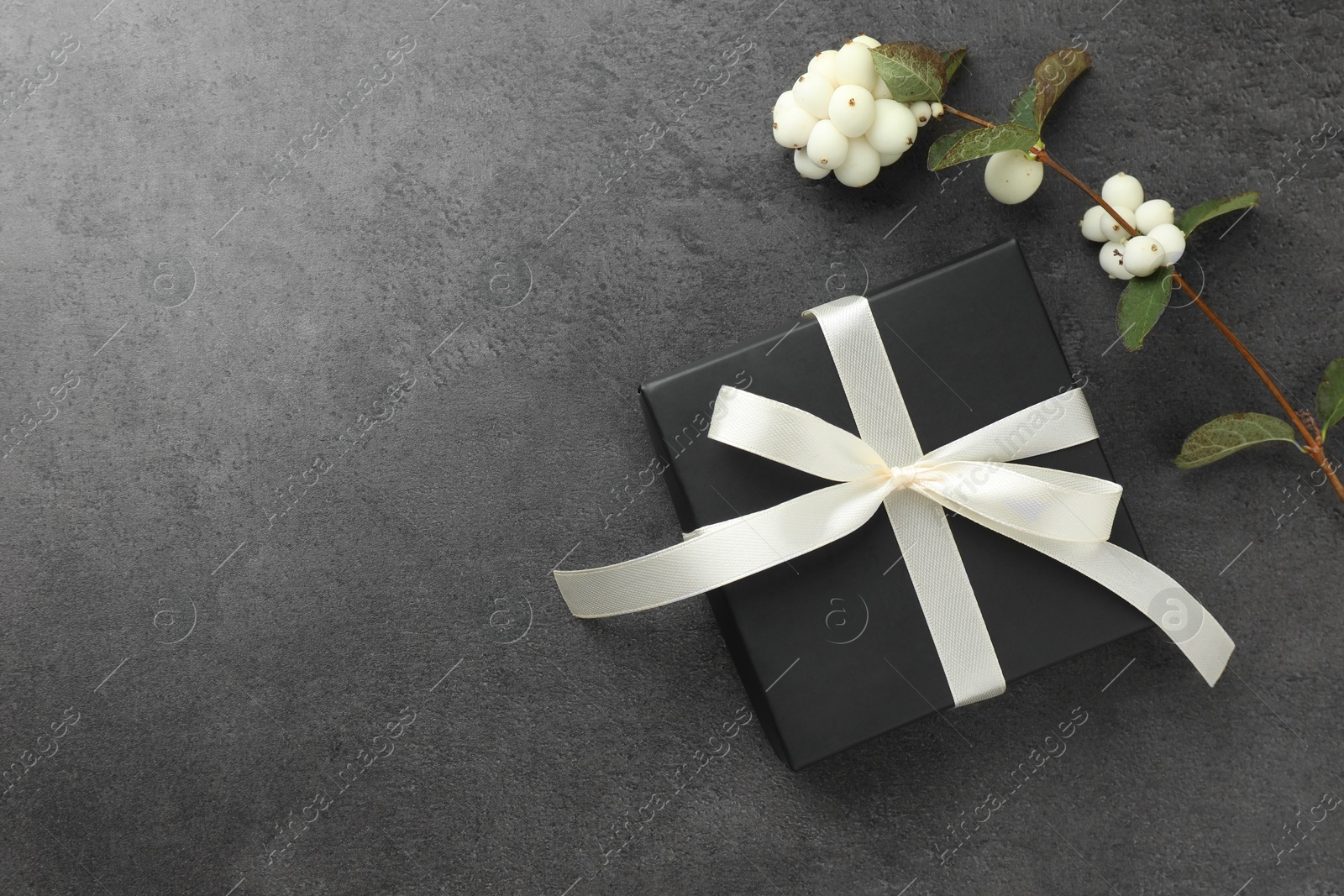 Photo of Gift box with bow and flowers on grey table, flat lay. Space for text