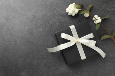 Photo of Gift box with bow and flowers on grey table, flat lay. Space for text