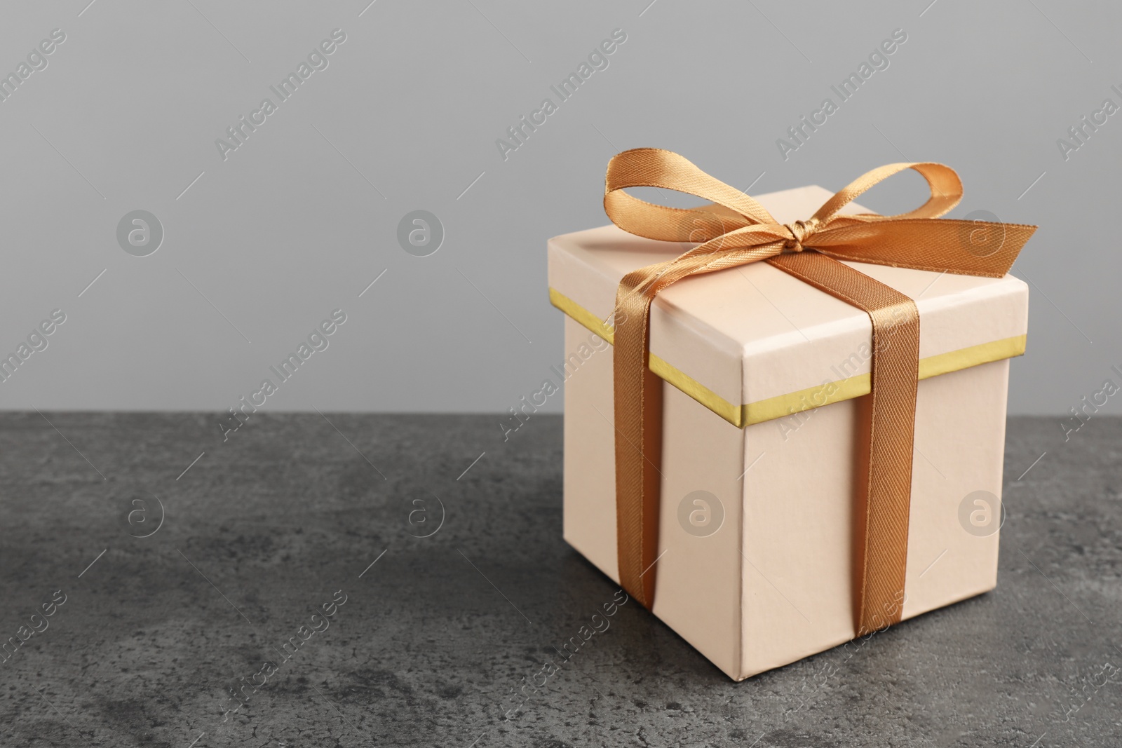 Photo of Gift box with bow on grey table, space for text