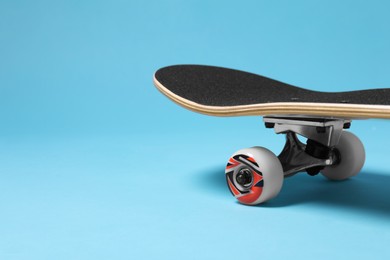 Photo of One skateboard on light blue background, closeup. Space for text