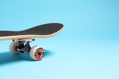 Photo of One skateboard on light blue background, closeup. Space for text