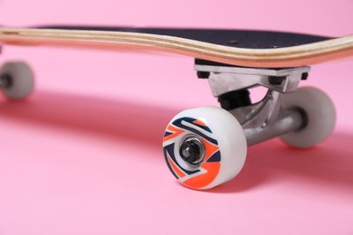 Photo of One skateboard on pink background, closeup. Sports equipment