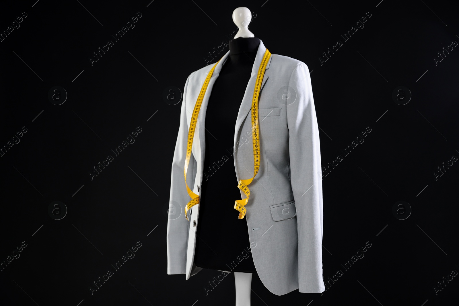 Photo of Female mannequin with gray jacket and measuring tape on dark background