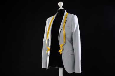 Photo of Female mannequin with gray jacket and measuring tape on dark background