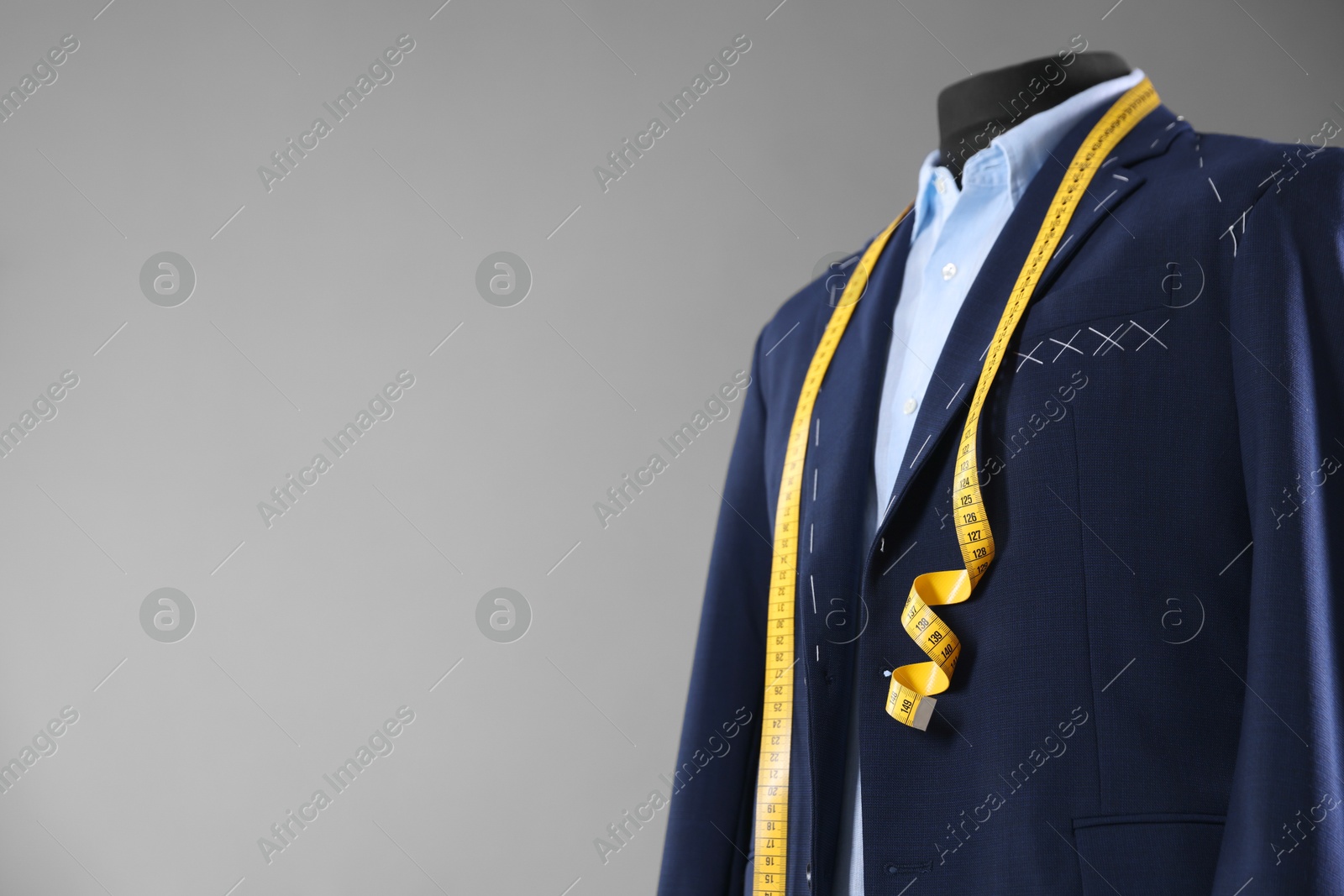 Photo of Semi-ready jacket, shirt and measuring tape on mannequin against gray background, space for text