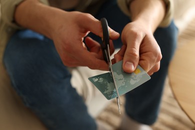 Photo of Man cutting his credit card indoors, closeup