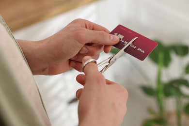 Photo of Man cutting his credit card indoors, closeup