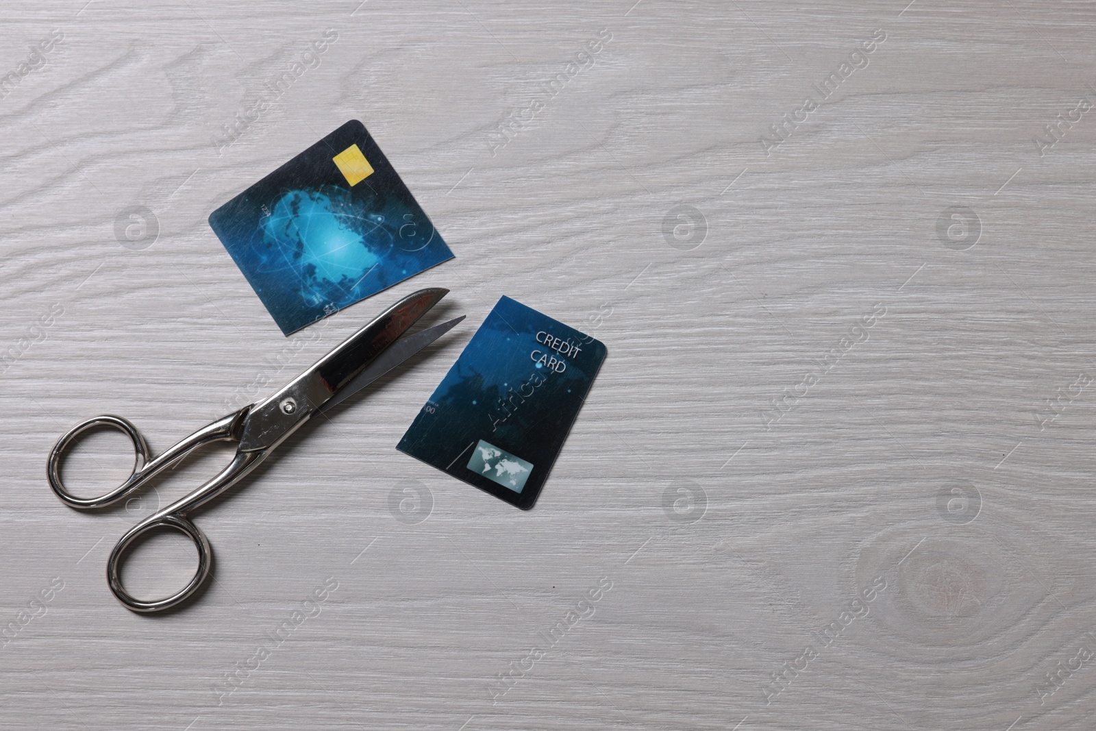 Photo of Pieces of credit card and scissors on white wooden table, top view. Space for text