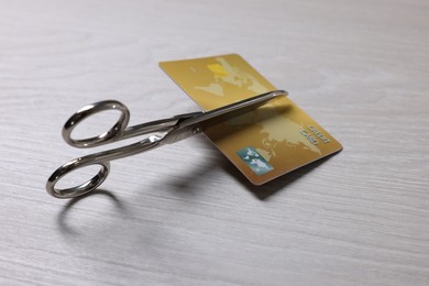 Photo of Credit card and scissors on white wooden table, closeup